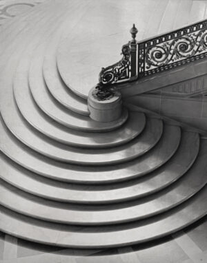 A black and white photo of stairs with a metal railing.