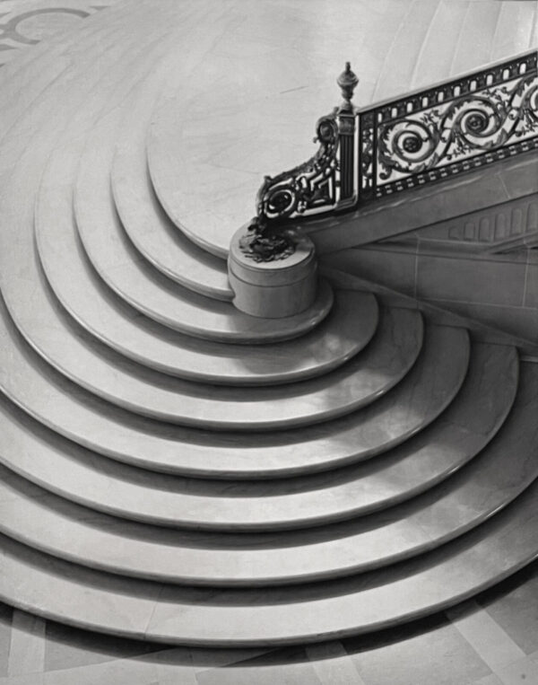 A black and white photo of stairs with a metal railing.