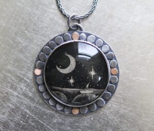 A necklace with a picture of the moon and stars.