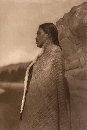 A woman standing in front of a stone wall.