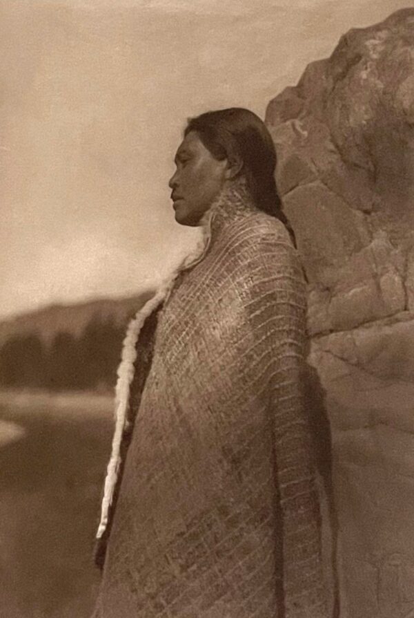 A woman standing in front of a stone wall.