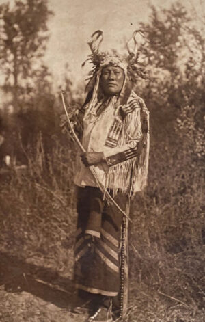 A man in native american garb standing on a pole.
