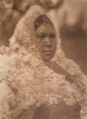 A woman in a fur coat is standing outside.
