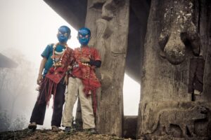 Two people in blue masks standing next to a tree.