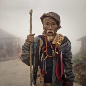 A man with a beard and hat holding a stick