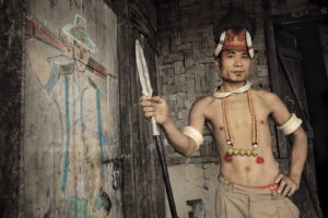 A man in native dress holding an arrow.