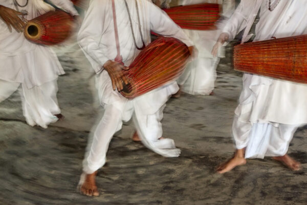 A group of people in white clothes holding bags.