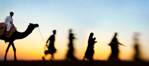 A blurry image of people walking in the desert