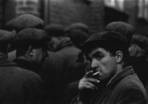 A man smoking a cigarette in front of other men.