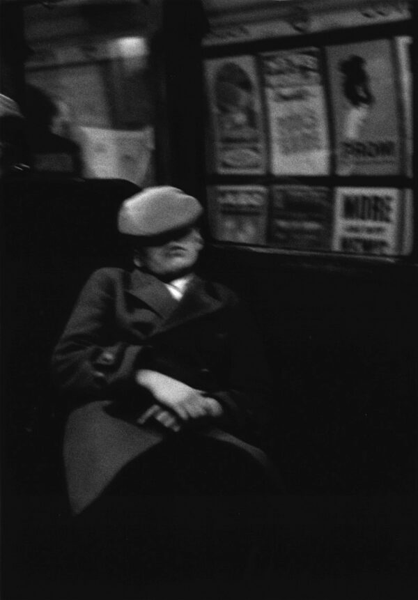 A man sitting on the subway in a hat.