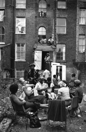 A group of people sitting around in front of some buildings