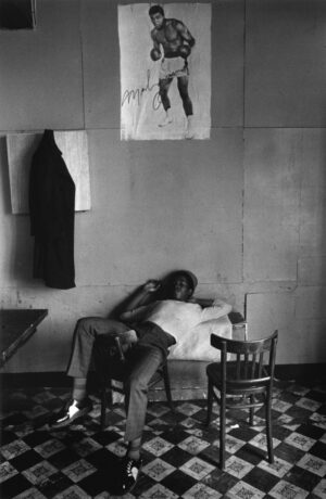 A man sitting on top of a chair in front of a wall.