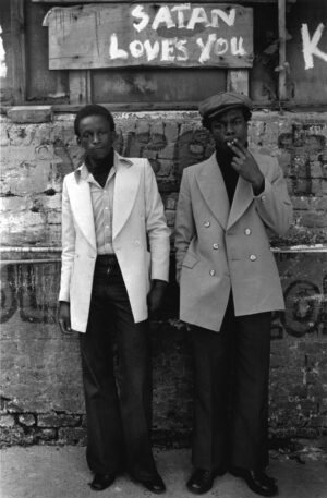 Two men standing next to each other in front of a wall.