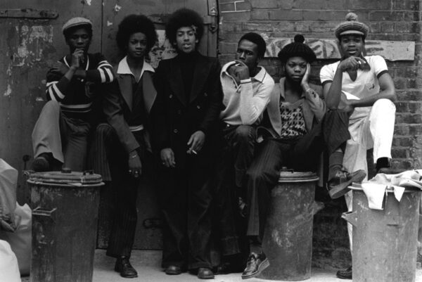 A group of people sitting on top of some wooden poles.