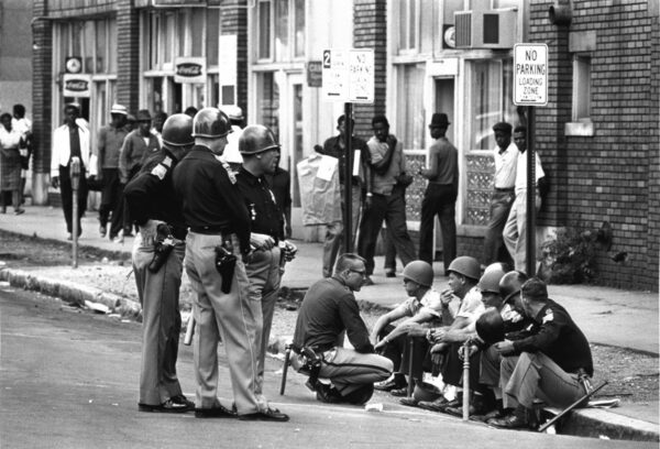 A group of people sitting on the side of a road.