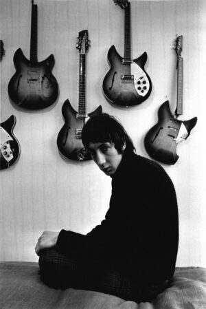 A man sitting in front of many guitars.