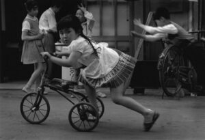 A girl is riding on the back of a bike.