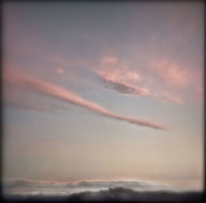 A pink sky with clouds and a few white lines