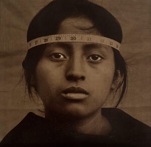 A young girl wearing a headband with measuring tape around her head.