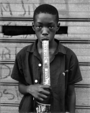 A young boy holding a stick in his mouth.