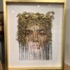 A framed picture of a woman 's face with leaves on it.