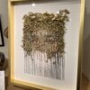 A framed picture of a face with gold leaves.