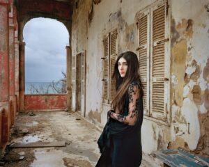 A woman standing in an abandoned building with windows.