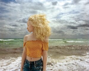 A woman standing on the beach with her hair blowing in the wind.
