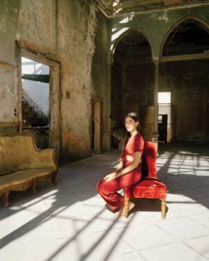 A woman in red sitting on an old chair.