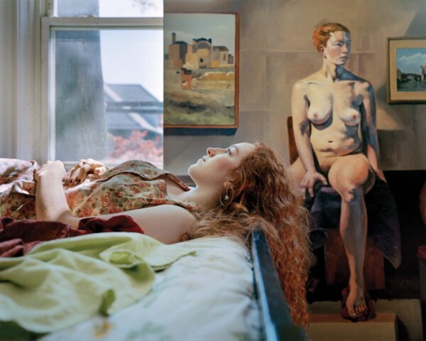 A woman laying on the bed next to a painting.