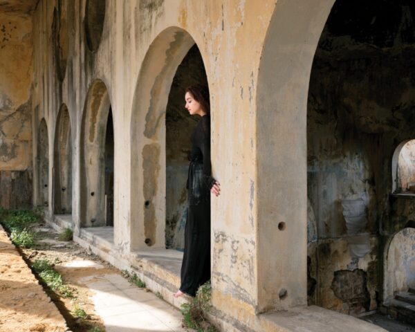 A woman in black dress standing inside of an archway.