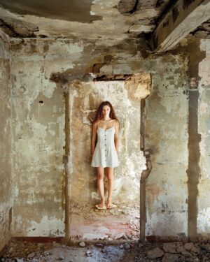 A woman in white dress standing inside of an old building.