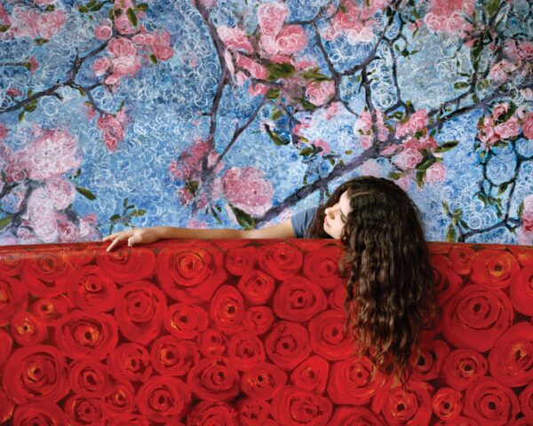 A woman leaning on the wall of roses
