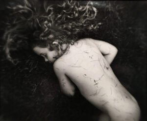 A woman with curly hair laying on the ground.