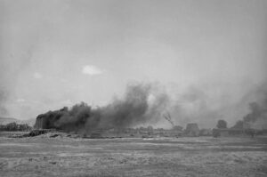 A black and white photo of smoke billowing from the ground.
