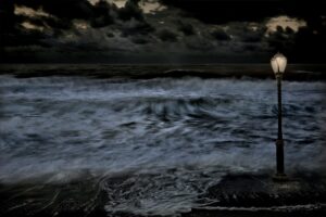 A dark picture of the ocean with waves crashing.