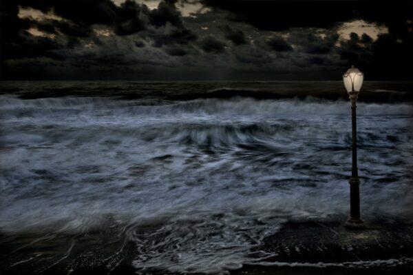 A dark picture of the ocean with waves crashing.