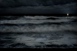 A dark picture of the ocean with waves crashing.