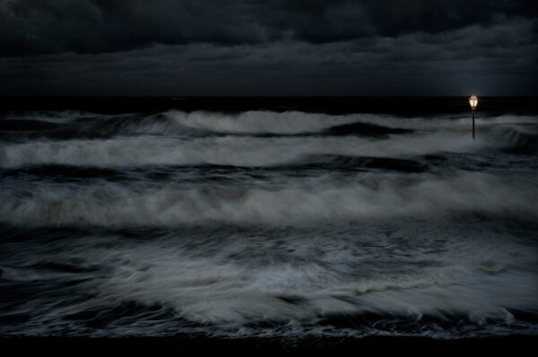 A dark picture of the ocean with waves crashing.