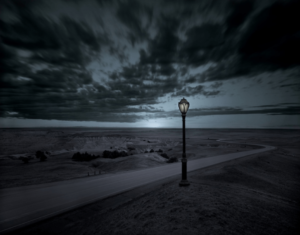 A lamp post on the beach at night.
