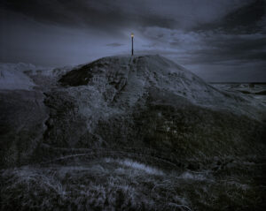 A cross on top of a hill in the dark.