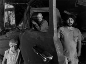 A man and two boys in an old car.