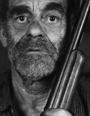 A man with a beard and mustache holding a rifle.