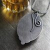 A silver leaf necklace sitting on top of a table.