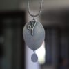 A silver necklace with a metal pendant hanging from it.