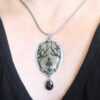A woman wearing a necklace with a black stone.