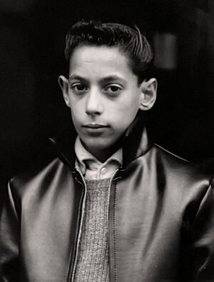 A young man in a leather jacket and tie.