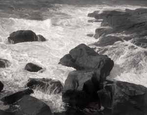 A black and white photo of rocks in the water.