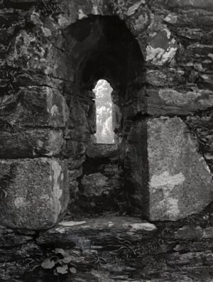A stone wall with a window in the middle of it.