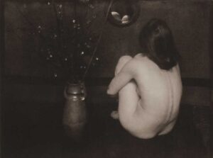 A woman sitting on the ground with her back to us.